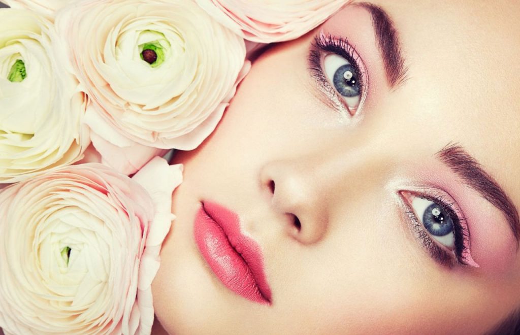 Makyajlı bir kadın yüzü ve yanında beyaz güller