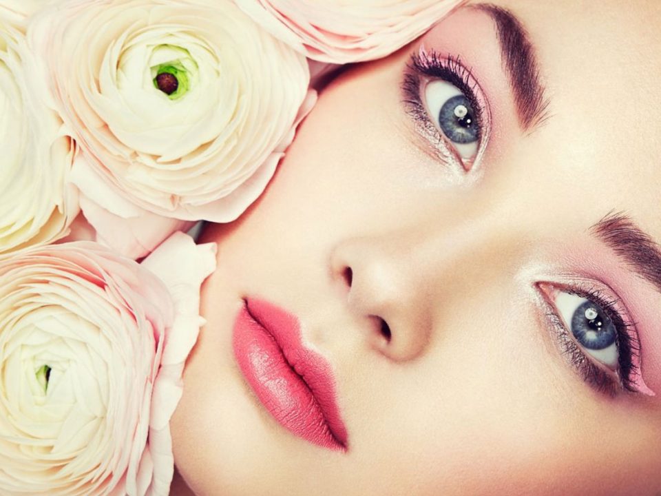 Makyajlı bir kadın yüzü ve yanında beyaz güller