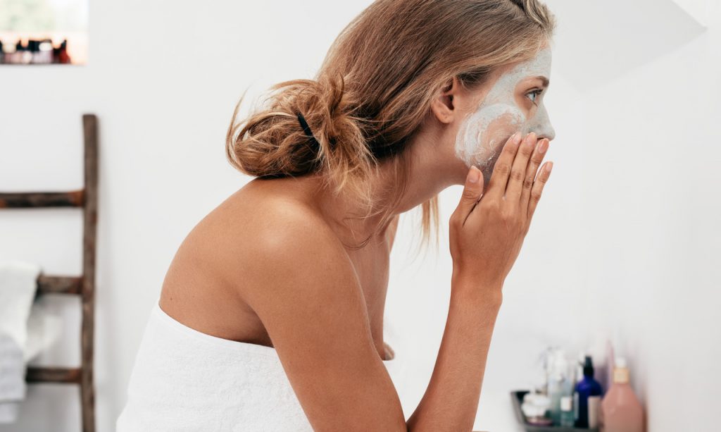 Banyoda cildine maya maskesi uygulayan saçları toplu kadın