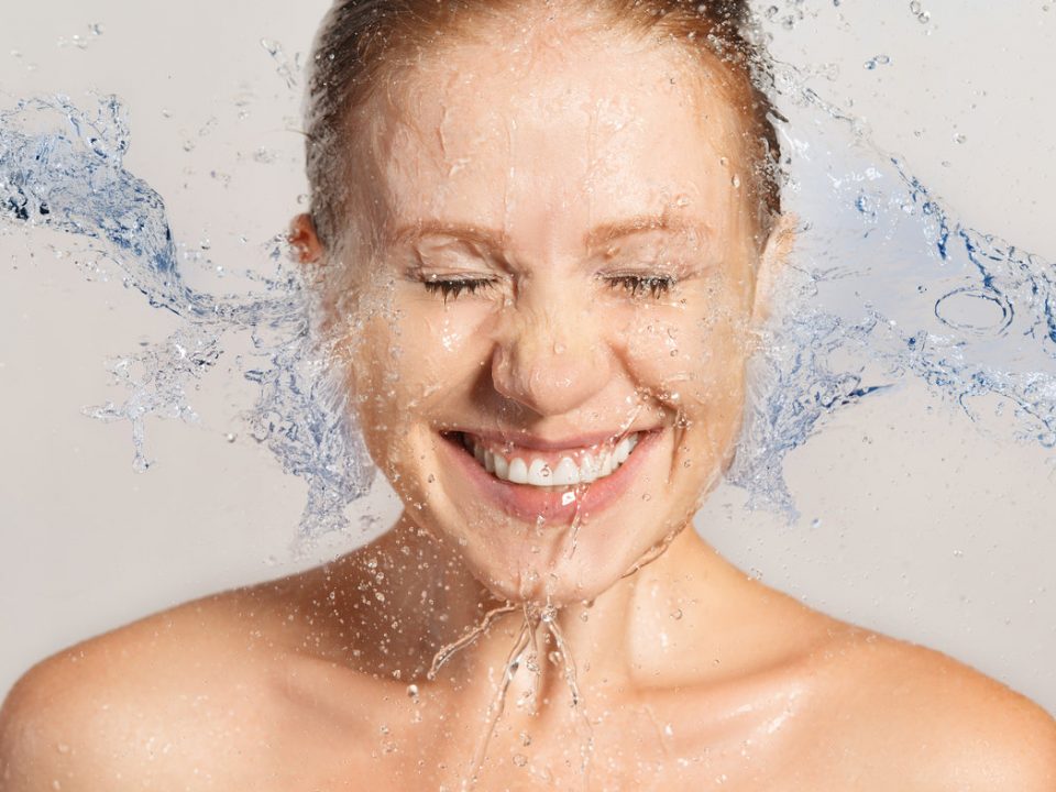Cilt temizliği sırasında yüzüne su çarparken gülümseyen kadın
